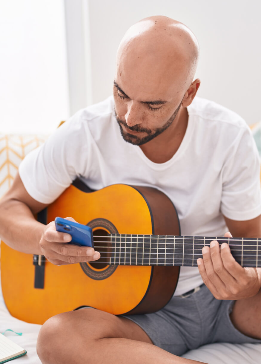 Man using phone while holding guitar