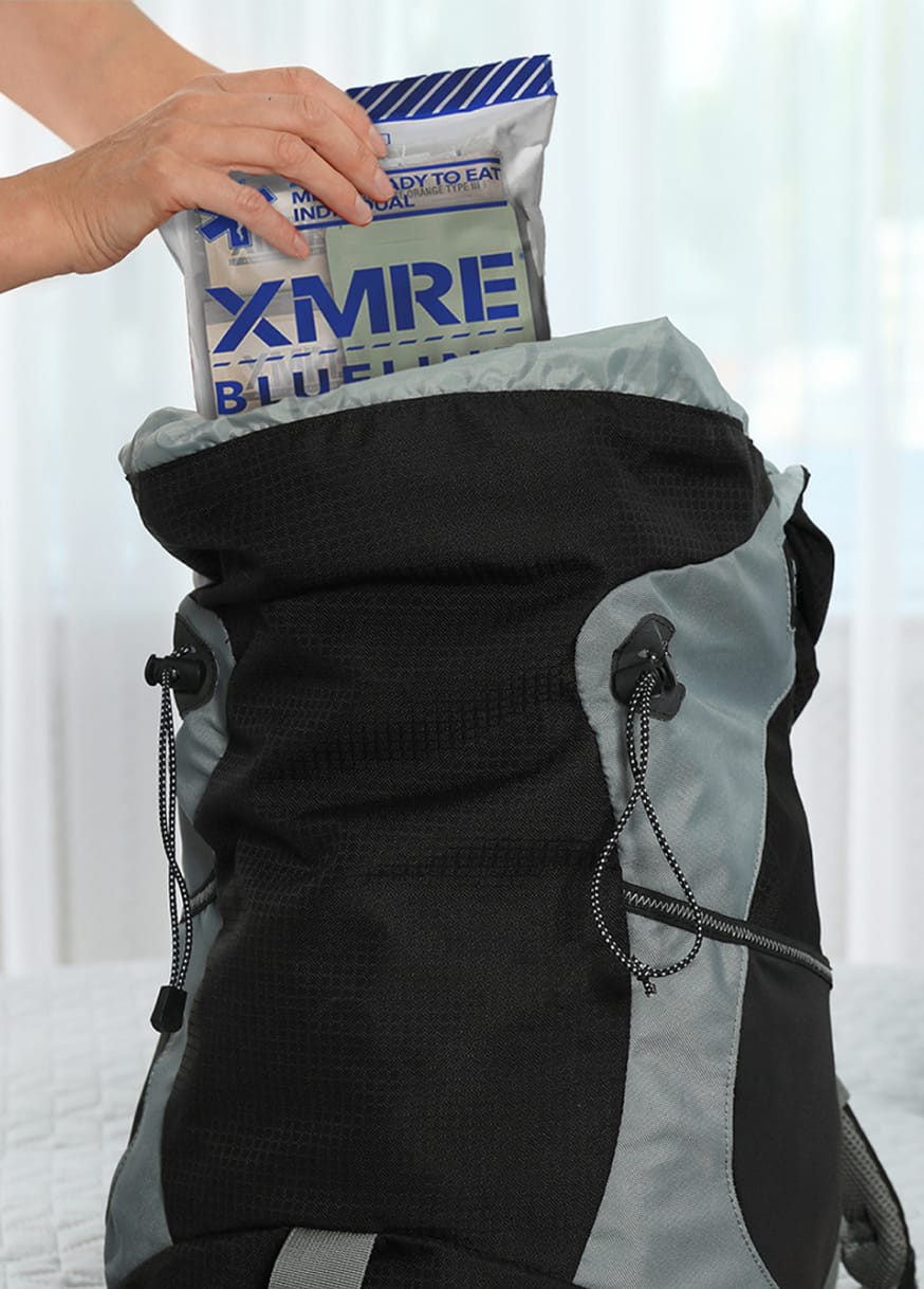 Person putting XMRE pack into bag
