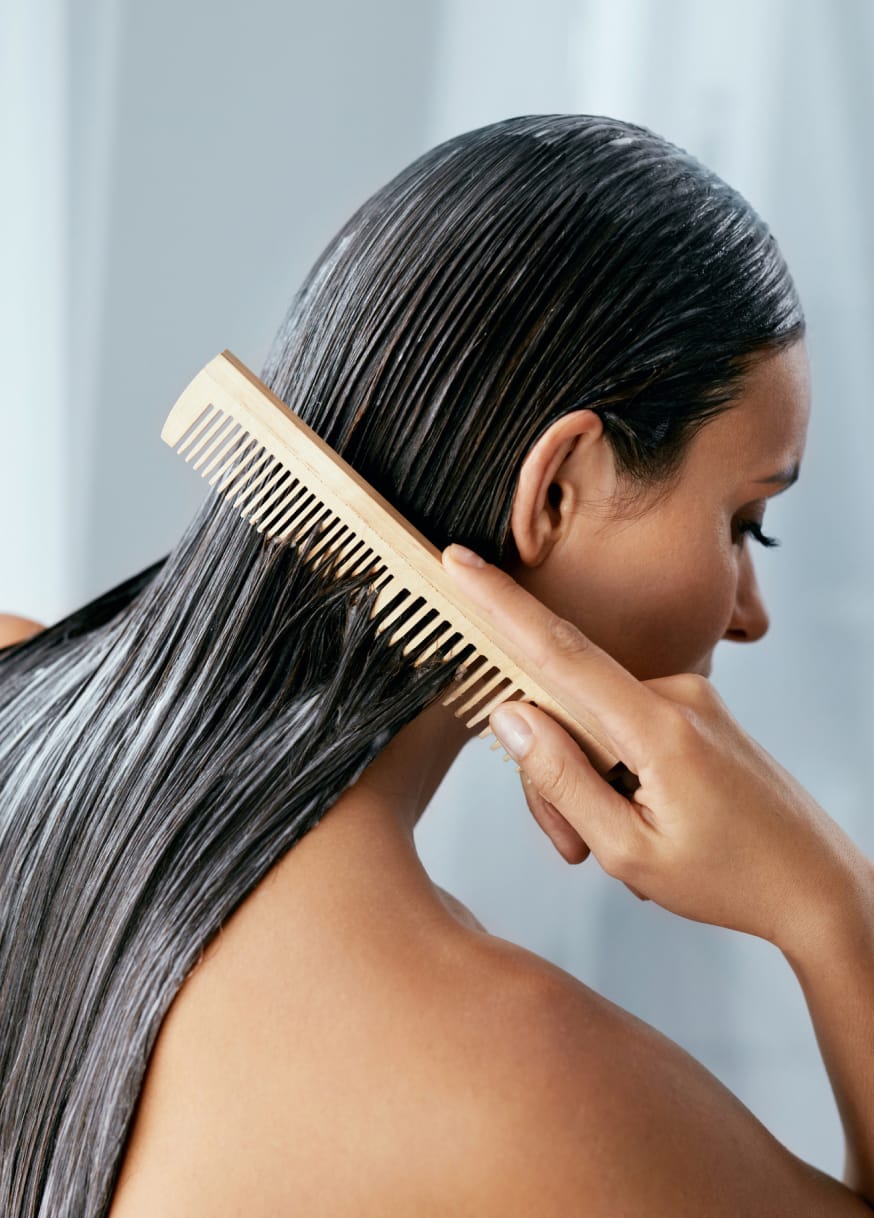 Woman combing conditioner through hair