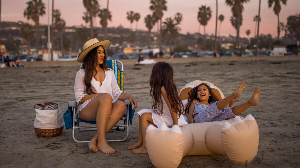 Woman and children lounging on the beach with Lightspeed Outdoors chair